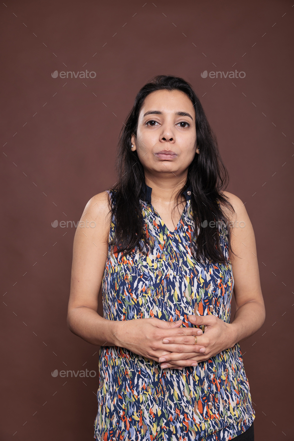 Indian woman with neutral facial expression, intertwined fingers portrait