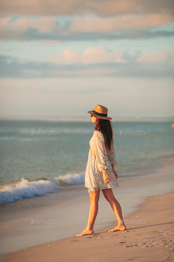 Young beautiful woman at straw hat on the beach at sunset - Stock Photo - Images