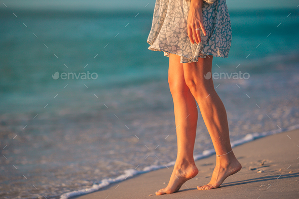 Female legs on the beach closeup. Woman in dress walking on the beach - Stock Photo - Images