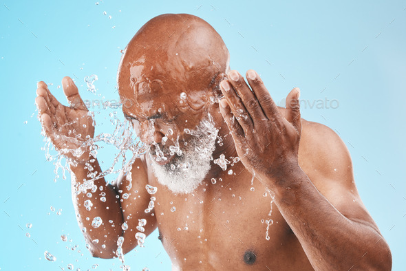 Black man cleaning face with water splash, healthy skincare on studio blue background for shower, c