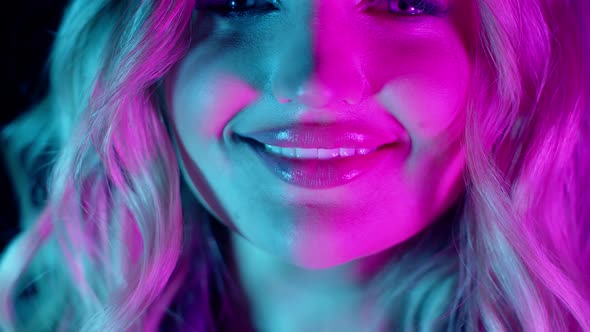 Sensual Blonde Girl with Bright Glowing Lipstick Seductively Smiling in Pink Green Neon Lights alt