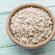 Raw oatmeal or oat flakes in a wooden bowl on a blue wooden background - PhotoDune Item for Sale