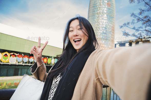 Happy asian young lady taking a selfie photo with an smartphone. Self portrait of chinese smiling