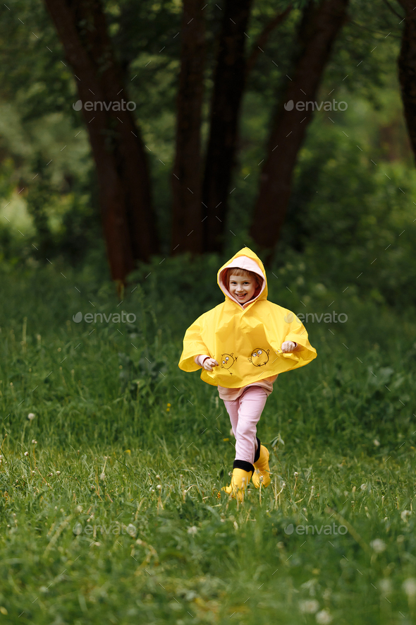 A girl in a yellow raincoat and yellow boots runs in the rain