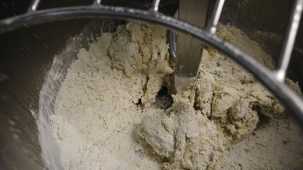Close-up of kneading dough in production mixer. Stock footage. Spiral kneader kneads fresh dough for