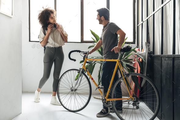 Multiracial friends meet at co working office entrance. Man with a bike, woman arrives at work.