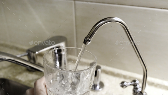 Water being poured into glass from kitchen tap. Concept. Close-up of tap water being poured into a