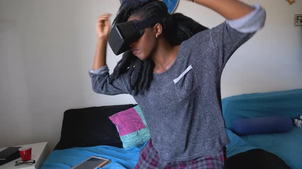 Slow motion shot of young woman wearing VR glasses dancing at home alt
