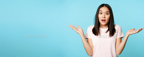 Confused asian girl spread empty hands sideways, shrugging shoulders clueless, standing in tshirt
