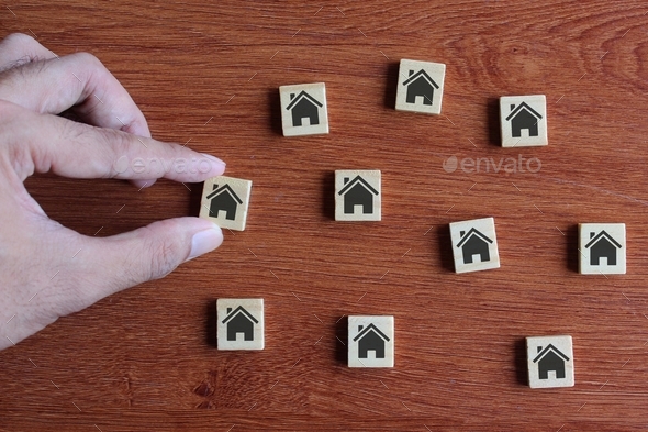 Hand pick wooden cubes with house icon.