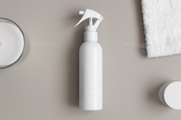 White cosmetic trigger sprayer bottle mockup with a towel on the beige table.