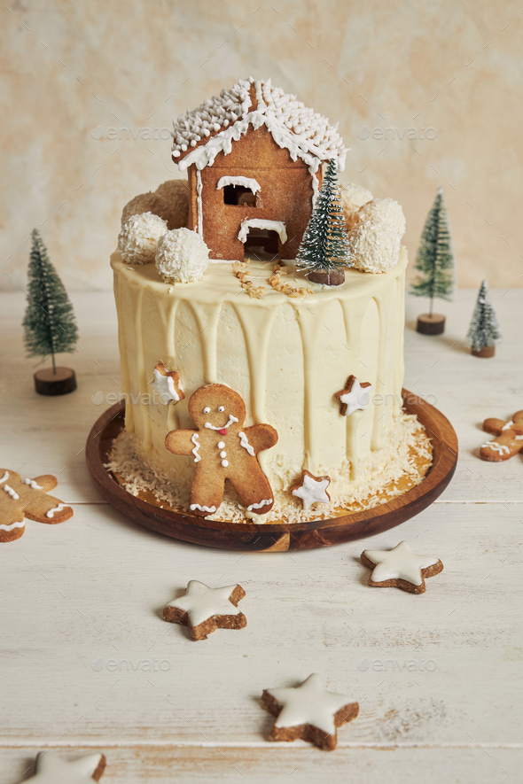 Vertical shot of a delicious Christmas drip cake with gingerbread  decorations on a white table Stock Photo by wirestock