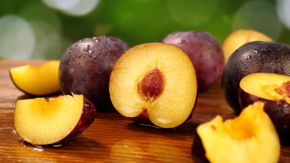 Cut Slice and Whole Plum on Wet Wooden Table