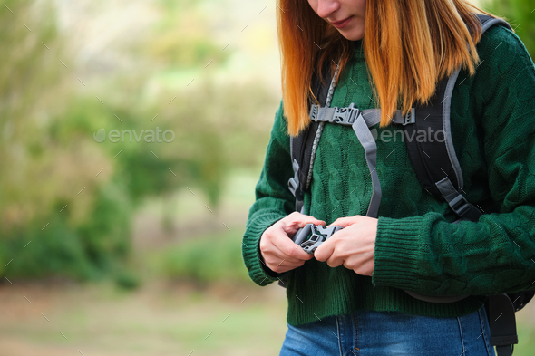 Close up of hiker redhead young woman fastening backpack strap in the mountain.