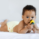 Cute African American Infant Baby Lying In Bed And Biting Toy - PhotoDune Item for Sale