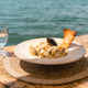 Seafood pasta spaghetti and a glass of water standing on a wooden table in outside cafe restaurant - PhotoDune Item for Sale