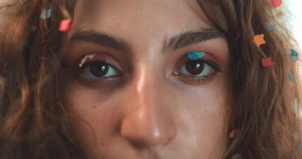 Close up of a girl covered in confetti with a charming gaze alt