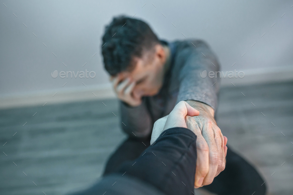 Unrecognizable man with problems receiving help from woman holding her hand - Stock Photo - Images