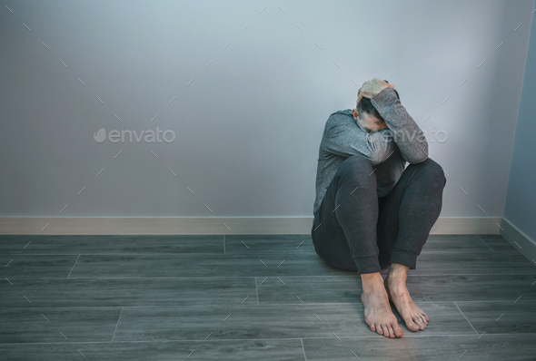 Unrecognizable man with problems sitting on floor - Stock Photo - Images
