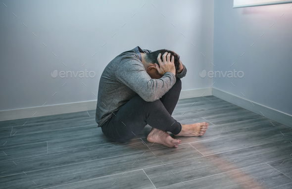 Unrecognizable man with problems sitting on the floor - Stock Photo - Images