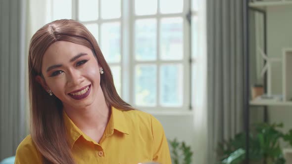 Influencer Young Transgender Woman Blogger Makeup. Looks And Smiles To Camera In Home Studio alt