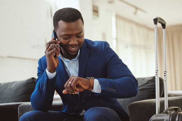 African businessman in hotel, on smartphone call and checking wrist watch for time. Corporate profe