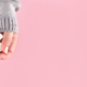 Hands in sweater with nude nails and white flower on pink background - PhotoDune Item for Sale