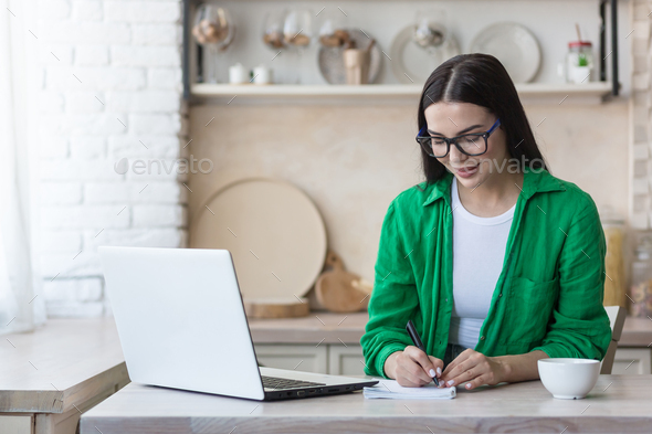 A young woman journalist, writer, blogger works remotely from home using a laptop online and notes
