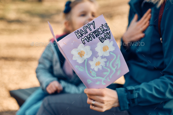 Close-up of mother receiving greeting card from her daughter on Mother's day.