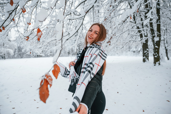 Leading the way. Beautiful young woman is outdoors in the winter forest