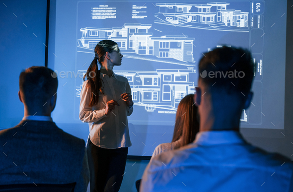 Female leader talking to employees, showing the plan on the projector in office