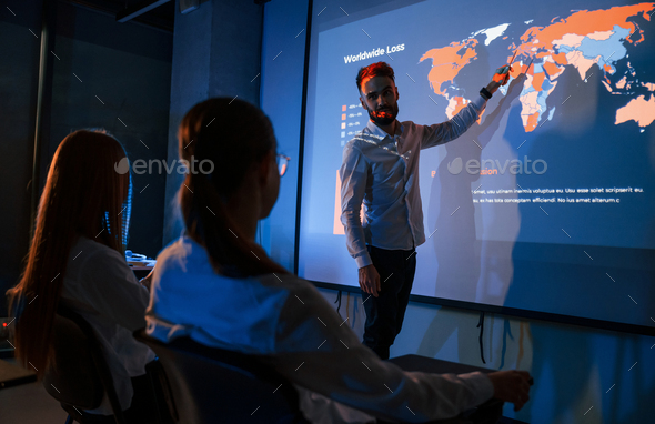 Male leader talking to employees, showing the plan on the projector in office