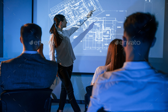 Female leader talking to employees, showing the plan on the projector in office