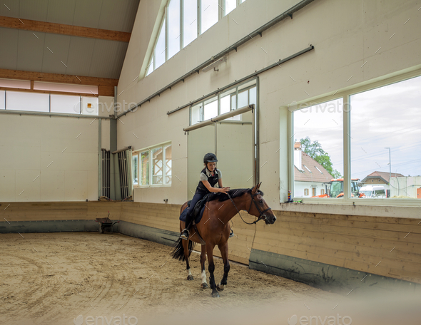 Closeup shot of a Slovenian girl riding a horse in an equestrian arena