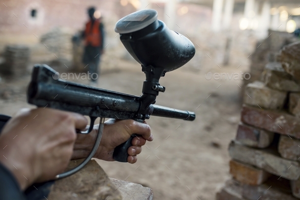 Closeup of a person playing paintball in an abandoned building under the lights