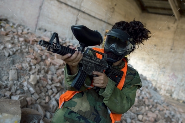 Person in a mask playing paintball in an abandoned building under the lights