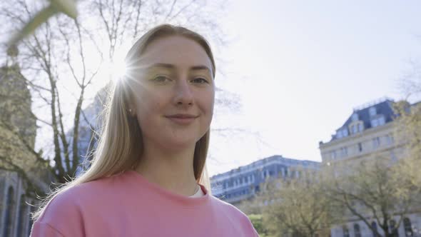 Pretty woman standing in city on a sunny day alt