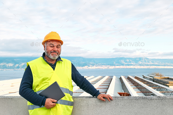 Smiling middle aged bearded supervisor in hardhat and safety vest with tablet on building site. - Stock Photo - Images