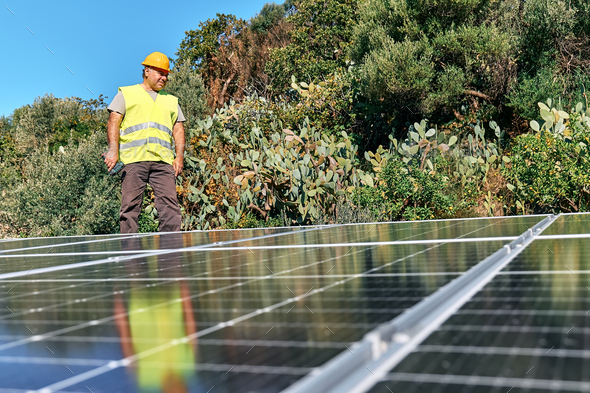 Professional worker with drill installing stand-alone photovoltaic solar panel system on the rooftop - Stock Photo - Images