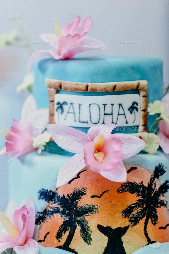 Vertical shot of a Hawaiian thematic cake decorated with pink flowers and \'aloha\' text