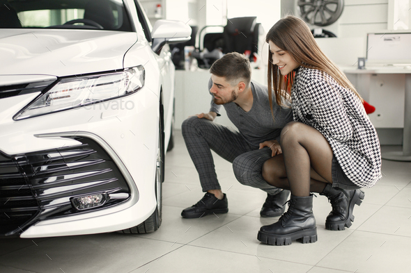 Caucasian young couple examining car at showroom - Stock Photo - Images