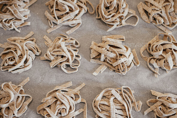 Homemade pasta. Dry fettuccine noodles in nests on baking tray close up.  Making whole-grain pasta Stock Photo by Sonyachny