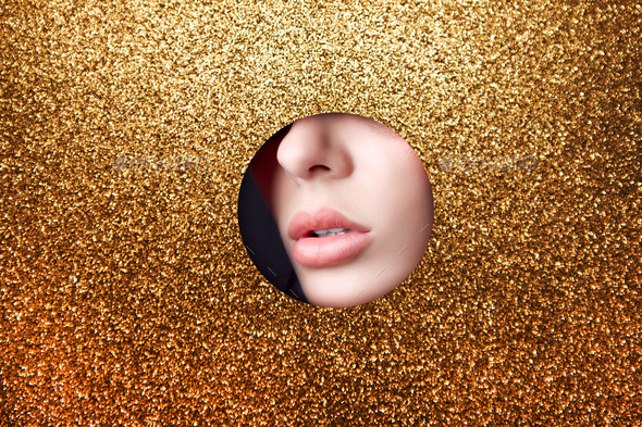 Beauty face red makeup plump lips of a young girl in a round slit hole of yellow gold paper