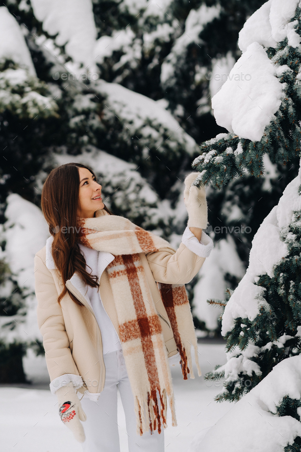 Portrait of a girl with long hair in mittens in a winter forest . Snowy winter - Stock Photo - Images