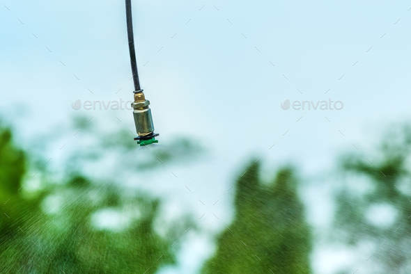 Agricultural sprinkler spraying the water drops over crops in cultivated field - Stock Photo - Images
