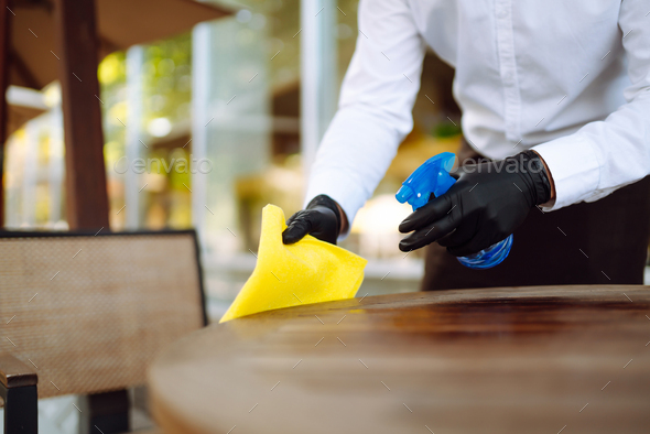 Waiter cleaning the table with spray disinfectant on table in