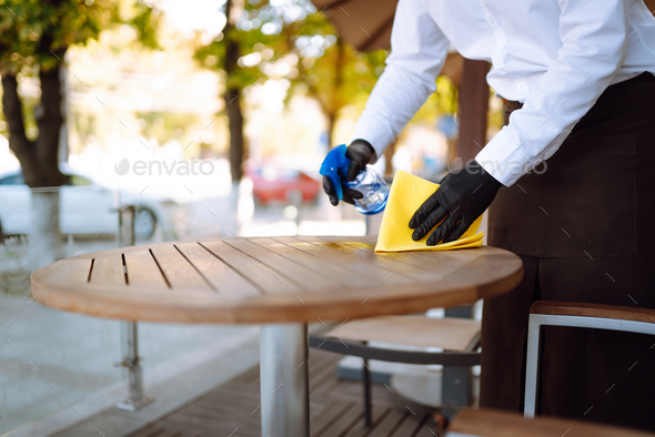 Waiter cleaning the table with spray disinfectant on table in