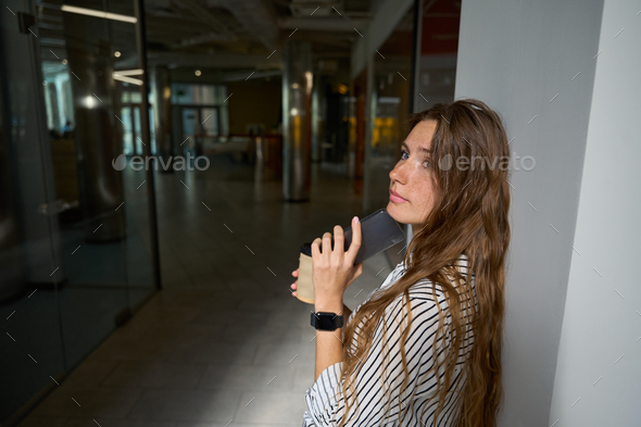 Young woman standing and holding coffee, phone - Stock Photo - Images