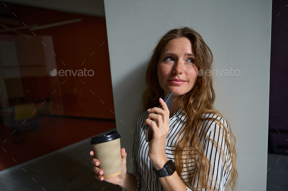 Thoughtful pretty woman holding smartphone and cup of coffee - Stock Photo - Images