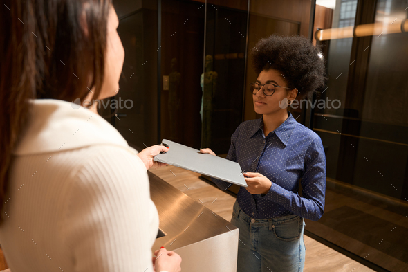 Pretty African American female taking documents at reception - Stock Photo - Images